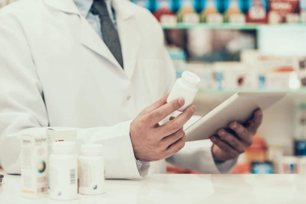 Closeup of a Pharmacist Holding Pills Bottle and Tablet. Pharmacy is out of your medication