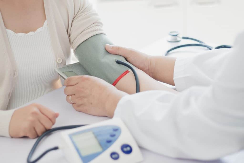 a doctor tests a patients blood pressure. This can lead to learning 5 ways to lower high blood pressure.
