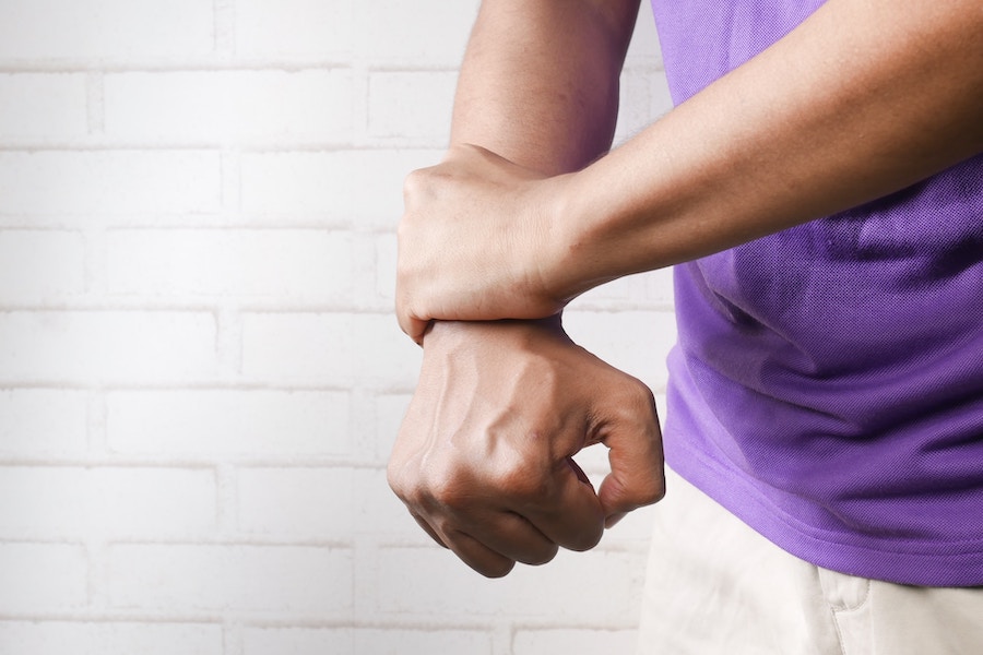 image of a man holding his wrist in pain, depicting one of the later stages of lyme disease - joint pain