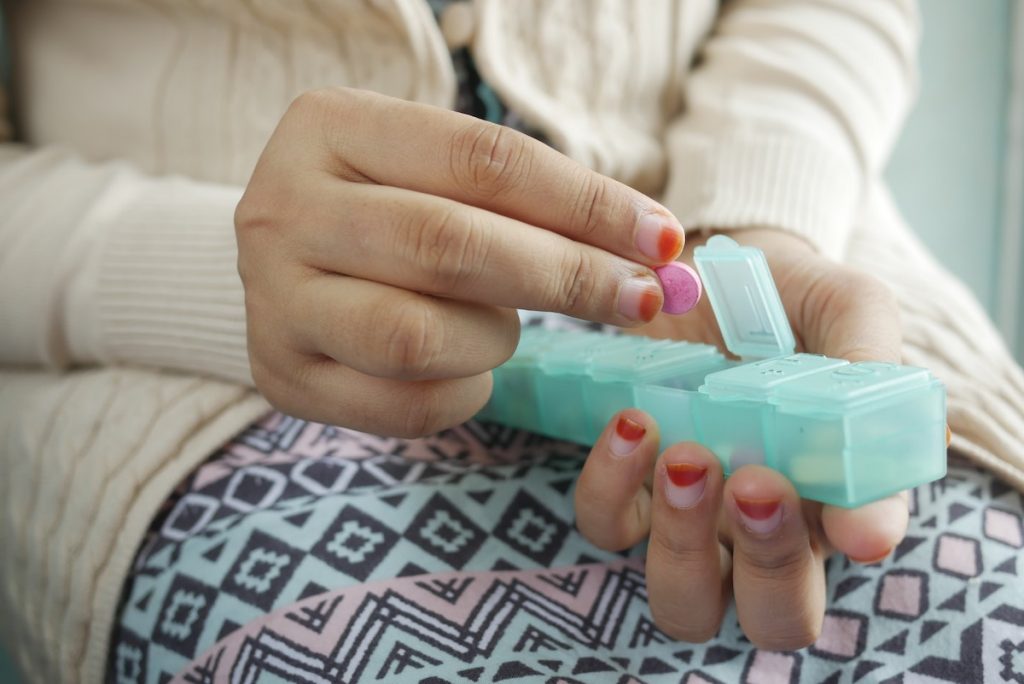 patient using a pill box to help with medication timings for Dexilant and other medications