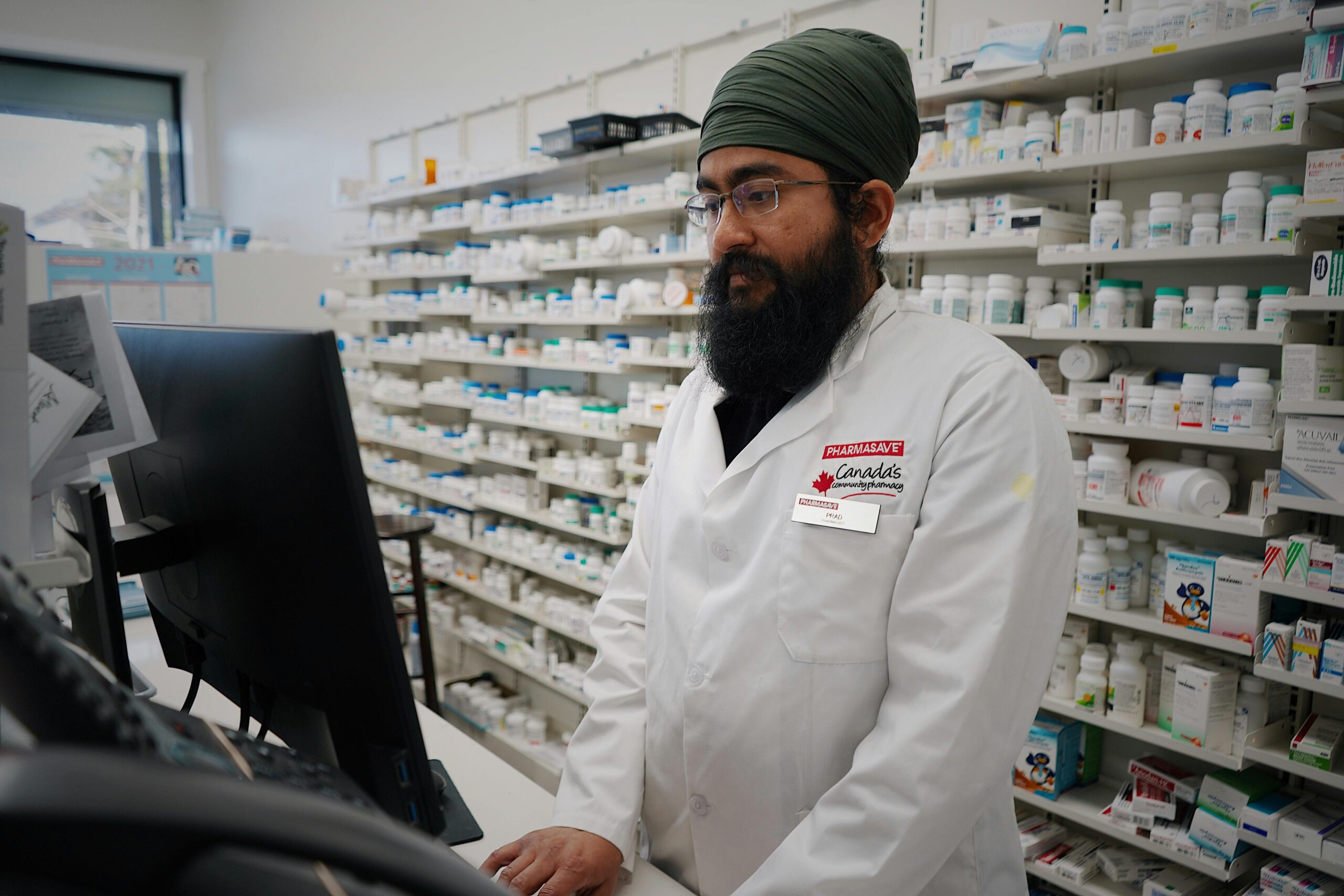 A pharmacist stands at his computer, symbolizing what people lose with pharmacy closures.