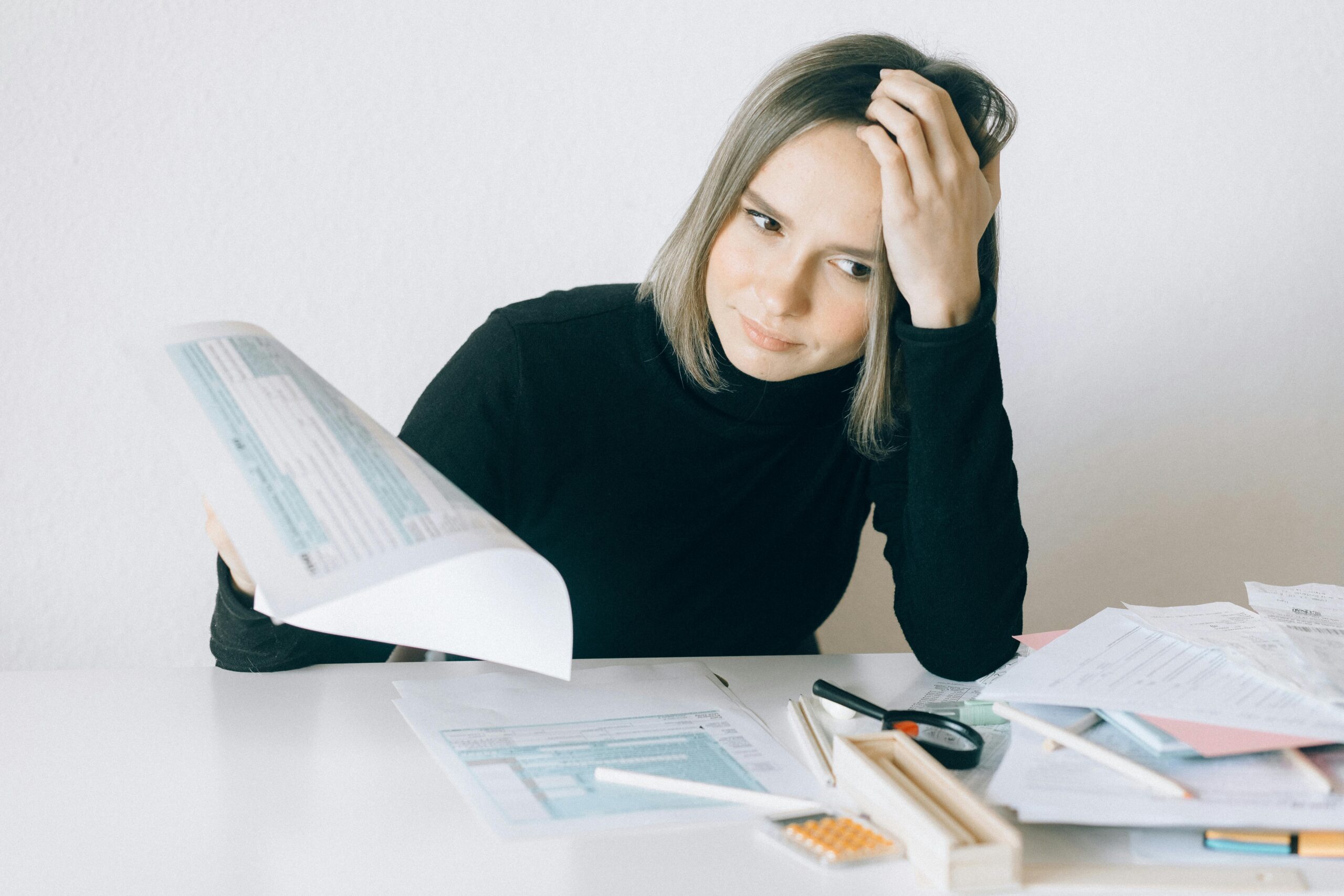 A woman looks stressed over a mess of paperwork because her medication isn't covered by insurance