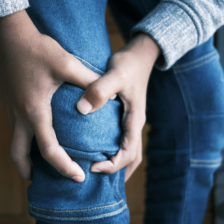 a person holds their knee due to rheumatoid arthritis, which may be managed with Actemra autoimmune therapy
