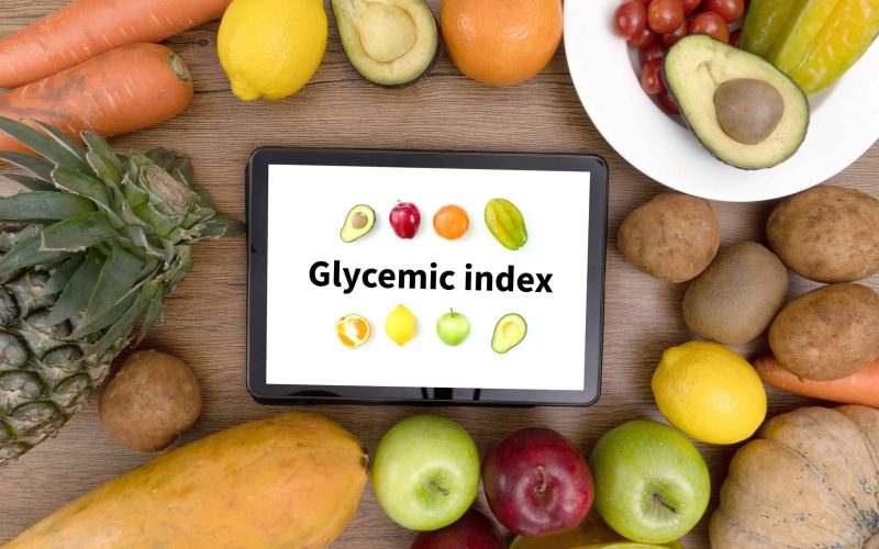 Glycemic index Fitness and weight loss concept, dumbbells, white scale, fruit and tape measure on a wooden table, top view