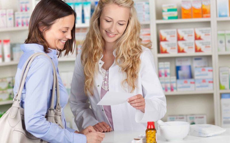 21174263 - young pharmacist and female customer reading prescription paper at pharmacy counter