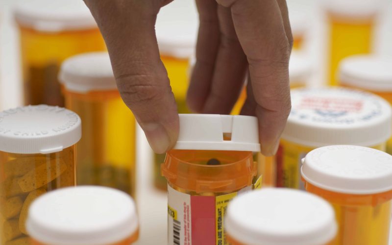 Man's hand opening pill bottle, close-up