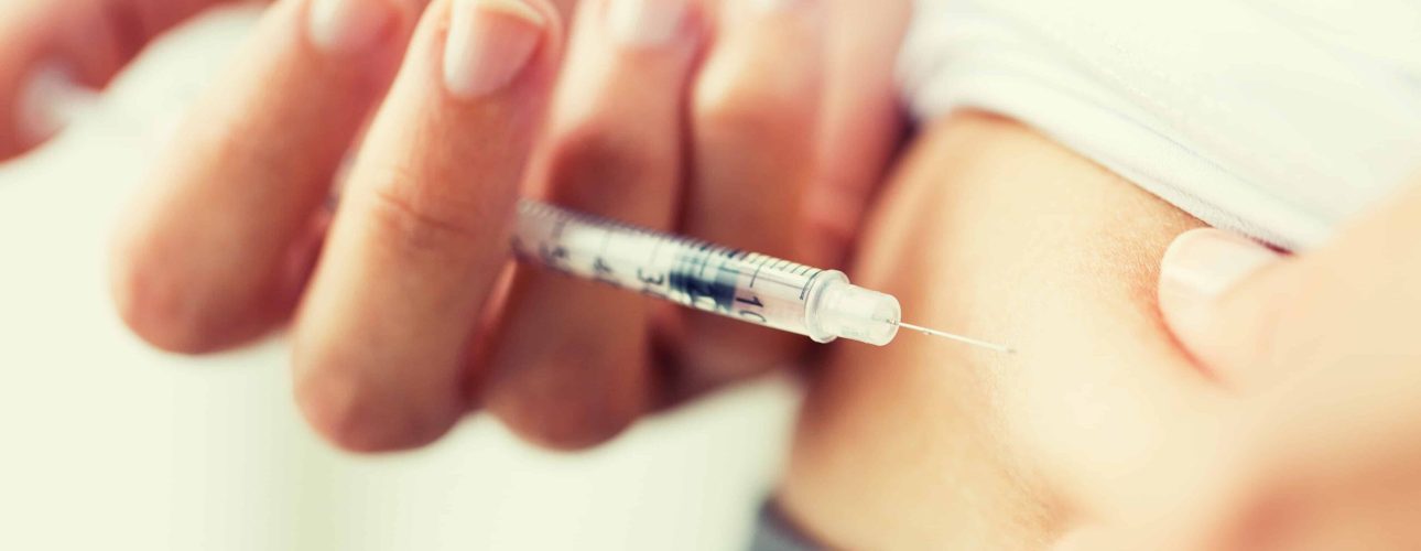 medicine, diabetes, glycemia, health care and people concept - close up of woman with syringe making insulin injection to himself at home