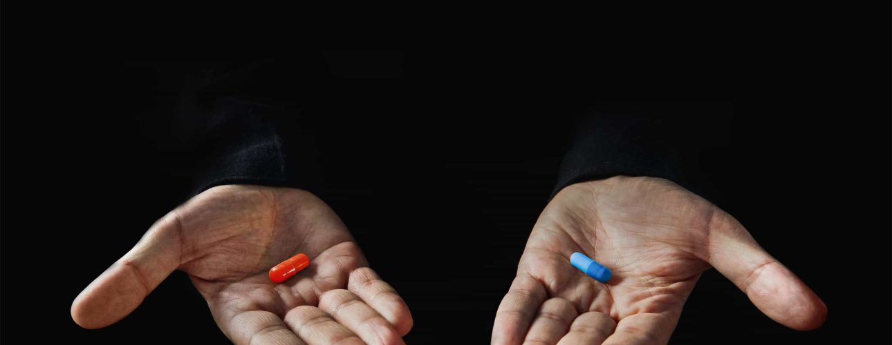 Red and blue pills on hand isolated on black background