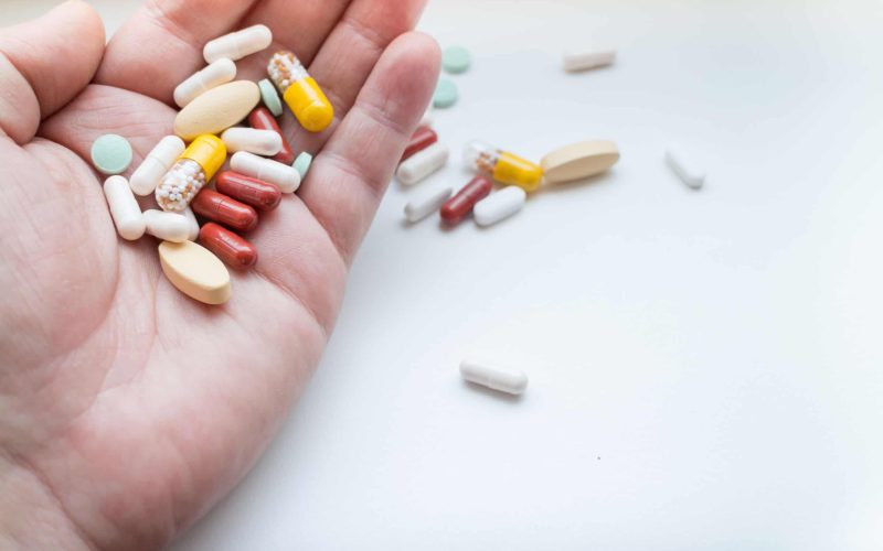 Assorted pills and tablets on hand, isolated on white background