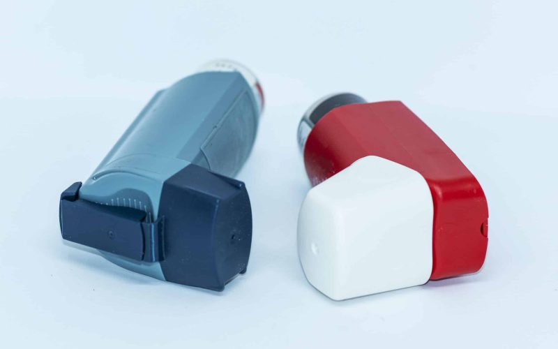 Two asthma inhalers with a white background lying next to each other.