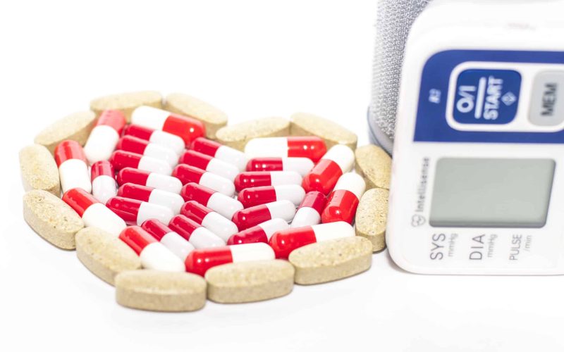 blood pressure device and tablets in heart-shaped arrangement, symbol photo of heart disease, diagnosis and medication