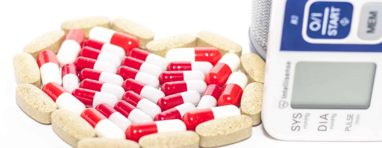 blood pressure device and tablets in heart-shaped arrangement, symbol photo of heart disease, diagnosis and medication