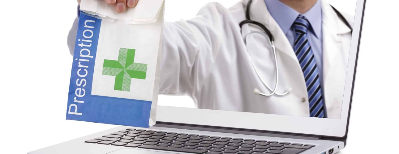 Internet drug store concept doctor holding prescription medicine through a laptop screen