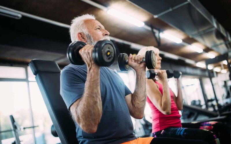 Senior fit couple exercising in gym to stay healthy