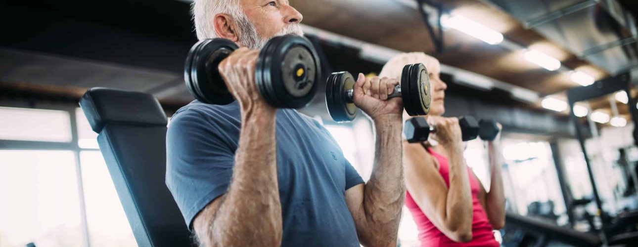 Senior fit couple exercising in gym to stay healthy