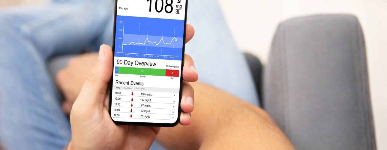 Man Holding Smartphone In Hand With Bad Level Of Blood Sugar On The Screen