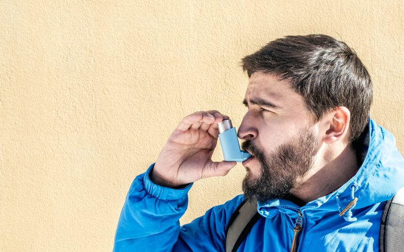 Portrait of young man using asthma inhaler outdoor