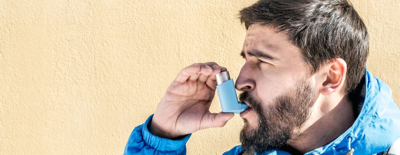 Portrait of young man using asthma inhaler outdoor