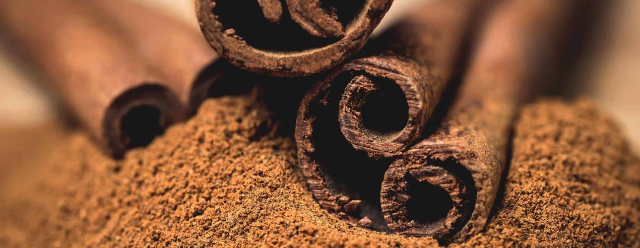 Cinnamon sticks with cinnamon powder on wooden background,