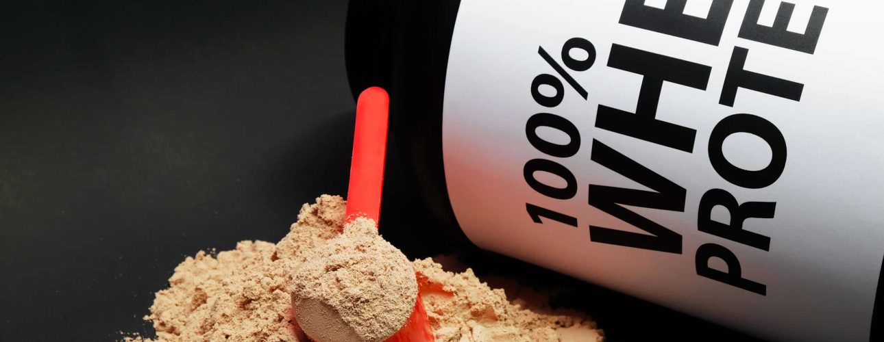 Whey Protein Powder in measuring scoop. Bodybuilding Nutrition Supplements.