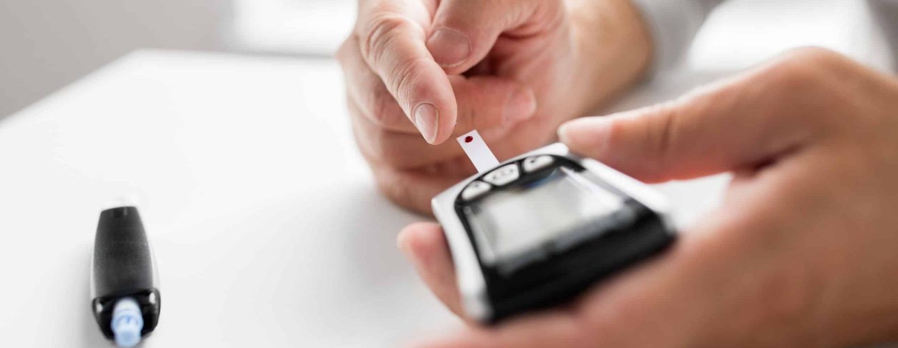 medicine, age, diabetes, health care and old people concept - senior man with glucometer checking blood sugar level at home