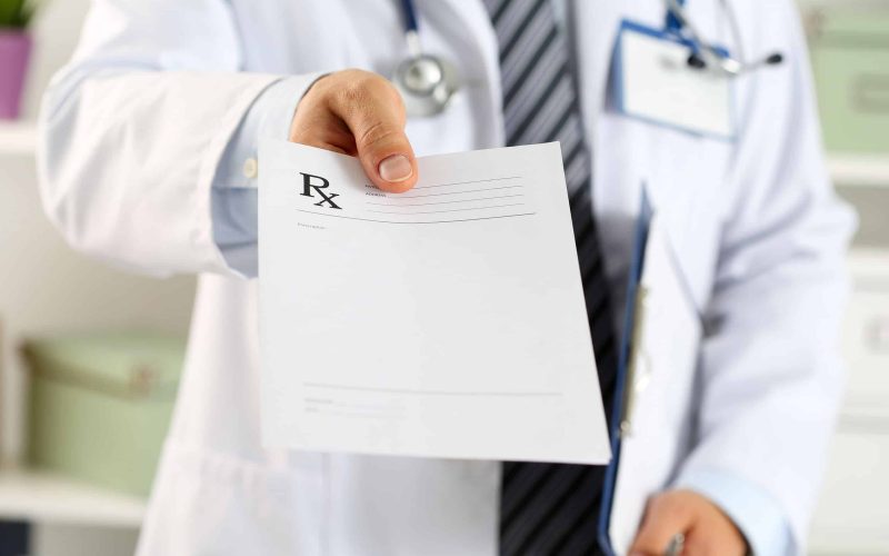 56354570 - male medicine doctor hand hold clipboard pad and give prescription to patient closeup. panacea and life save, prescribe treatment, legal drug store, contraception concept. empty form ready to be used