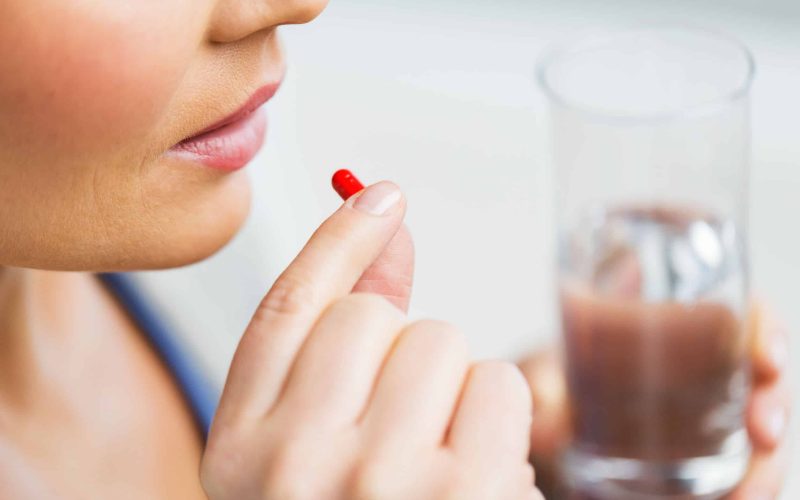 medicine, health care and people concept - close up of woman taking in pill