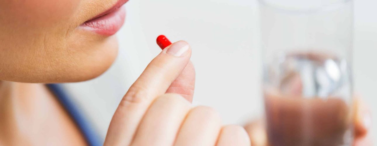 medicine, health care and people concept - close up of woman taking in pill