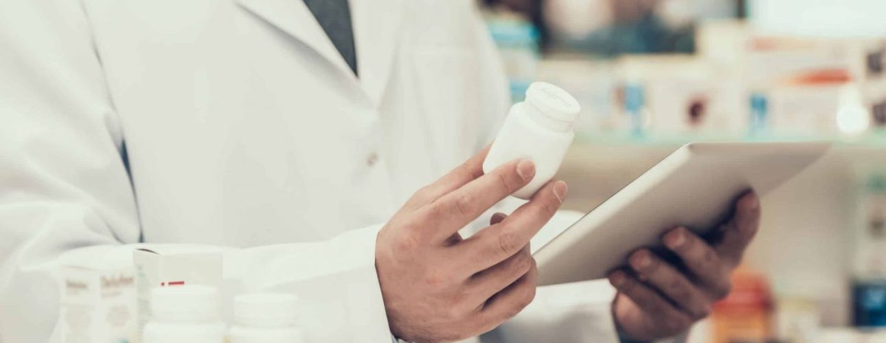 Closeup of a Pharmacist Holding Pills Bottle and Tablet.