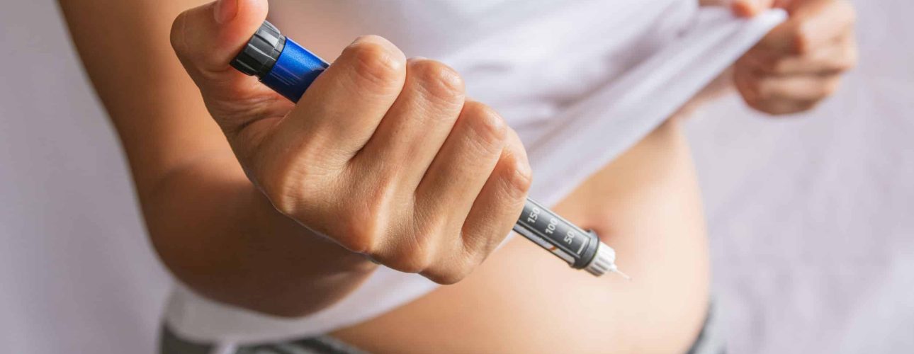 Diabetes concept insulin syringe injection shot into abdomen