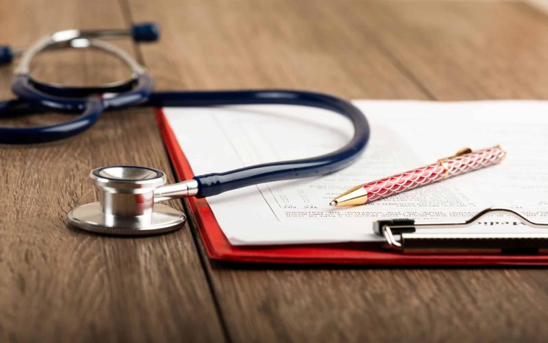 medical history with stethoscope and pen on wooden desk