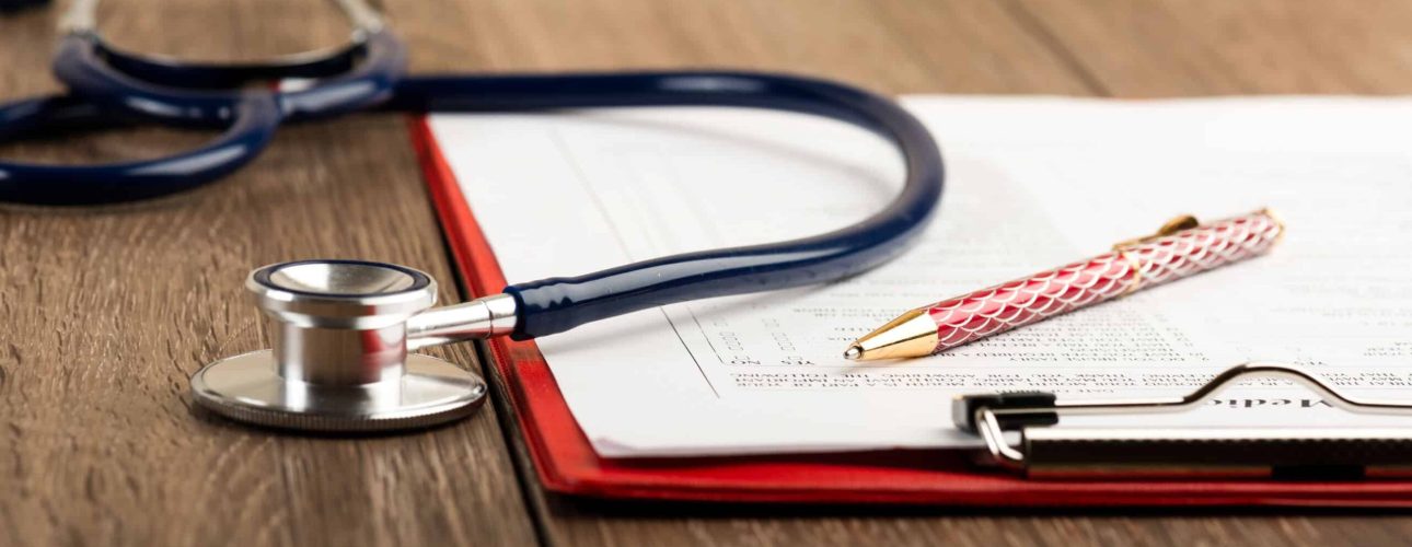 medical history with stethoscope and pen on wooden desk