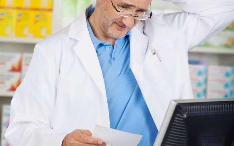 21246448 - confused mature pharmacist holding prescription paper at pharmacy counter