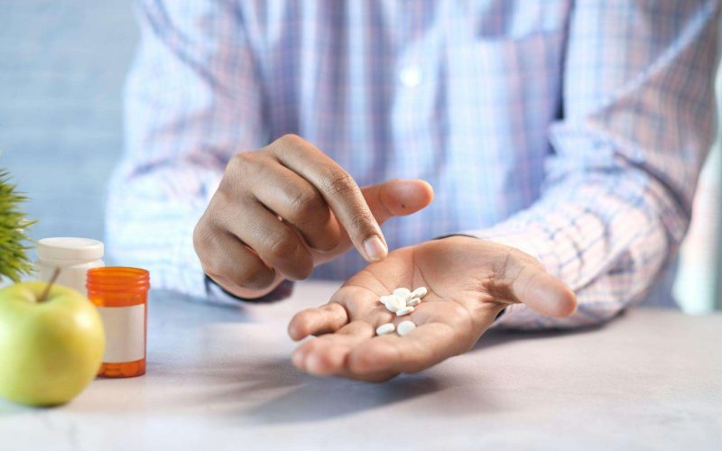 Person holding Eliquis tablets in an open hand beside a pill bottle