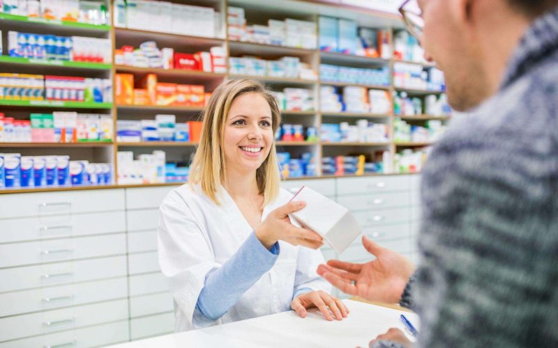 Jardiance pharmacist handing a medication box to a customer at the pharmacy counter